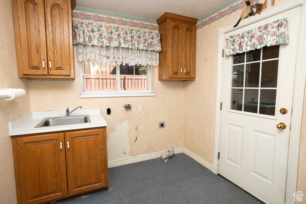 Laundry area with hookup for an electric dryer, sink, a textured ceiling, dark colored carpet, and cabinets