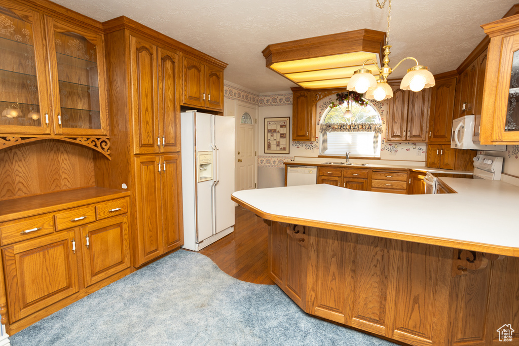 Kitchen with kitchen peninsula, sink, decorative light fixtures, a chandelier, and white appliances