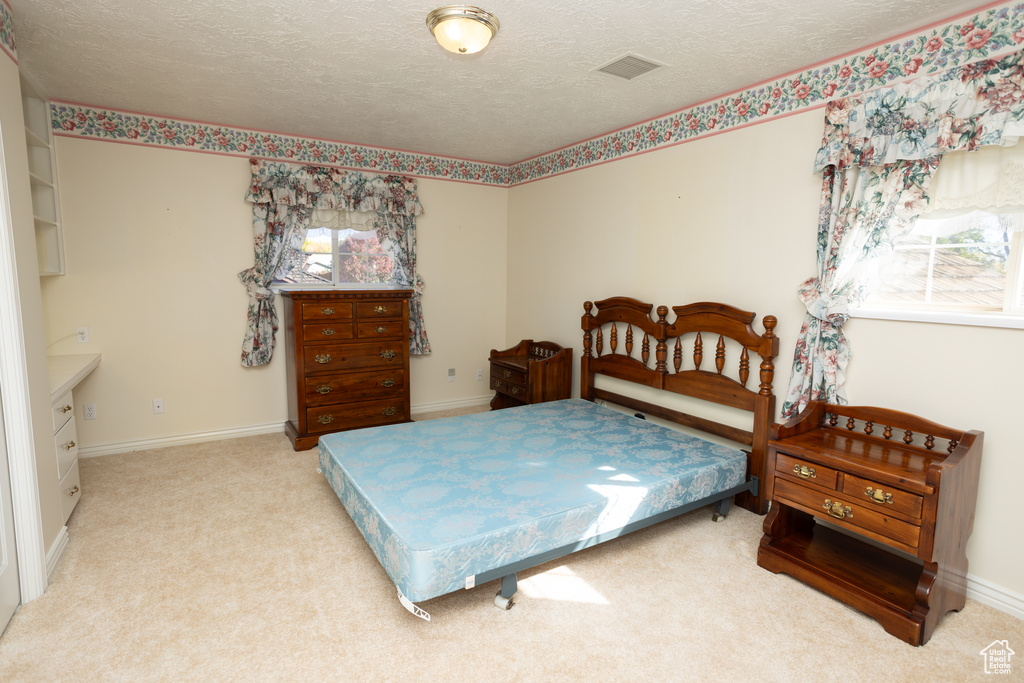 Bedroom with a textured ceiling and light colored carpet