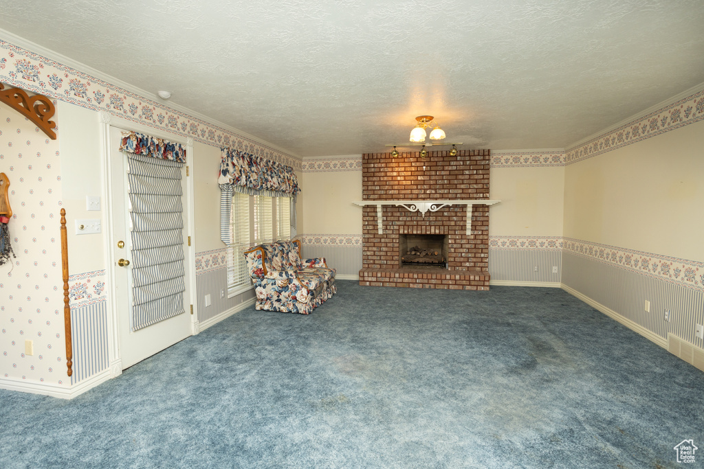 Unfurnished living room with crown molding, a textured ceiling, carpet flooring, and a fireplace