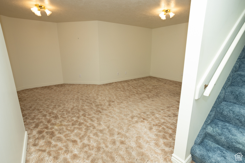 Unfurnished room featuring a textured ceiling and light colored carpet