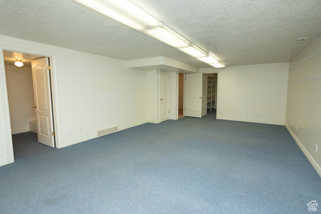 Basement with a textured ceiling and carpet flooring