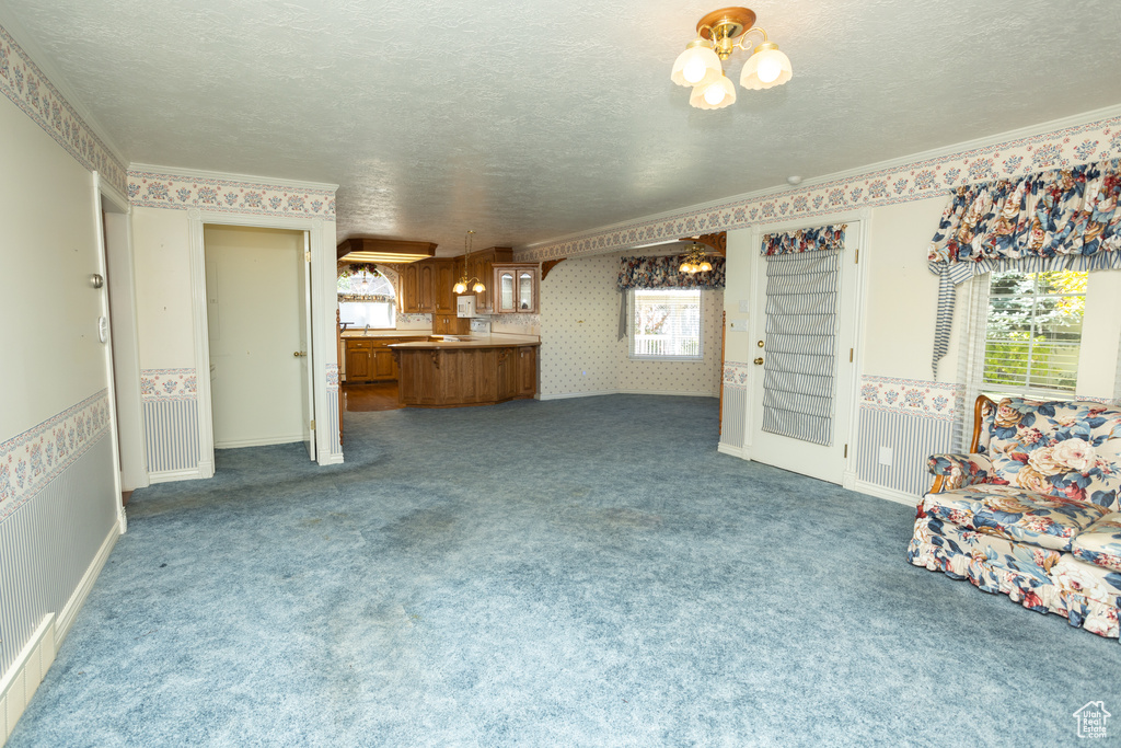 Unfurnished living room featuring carpet, a textured ceiling, and a healthy amount of sunlight