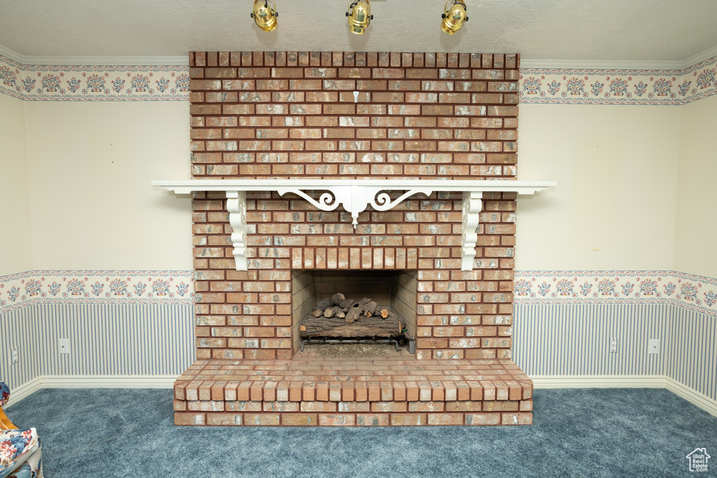 Room details featuring ornamental molding, a textured ceiling, carpet flooring, and a brick fireplace