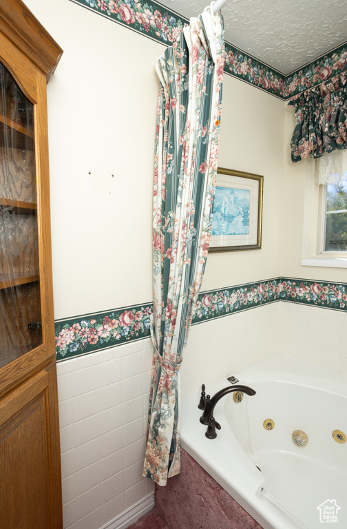 Bathroom featuring tile walls, a textured ceiling, and a washtub