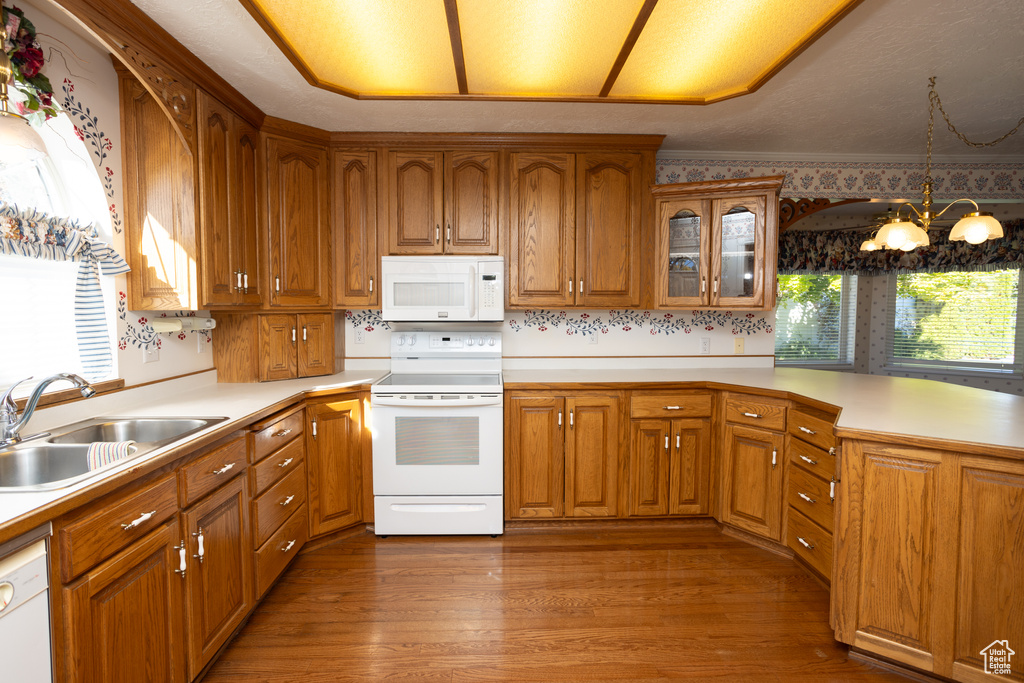 Kitchen with hanging light fixtures, hardwood / wood-style floors, sink, an inviting chandelier, and white appliances