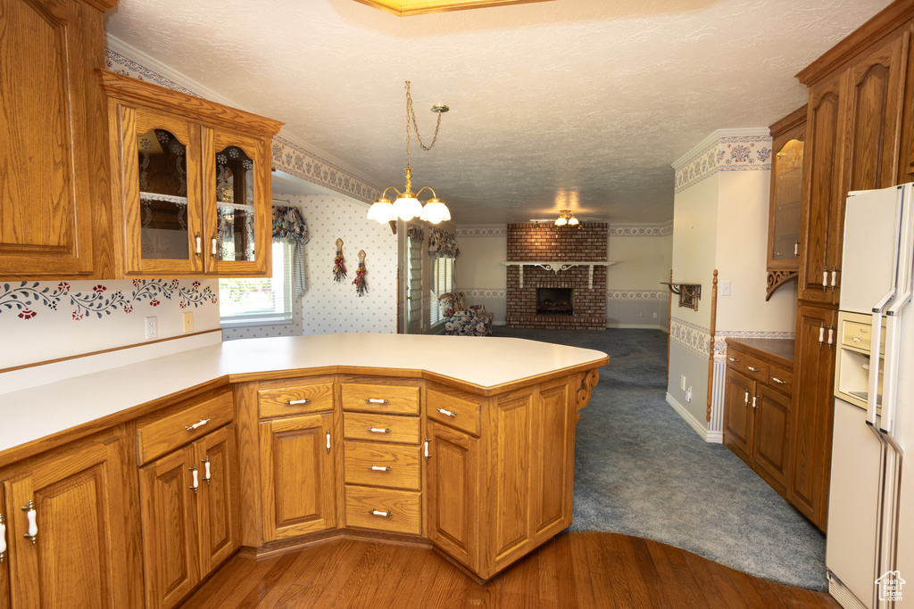 Kitchen featuring white fridge with ice dispenser, kitchen peninsula, dark hardwood / wood-style floors, and hanging light fixtures