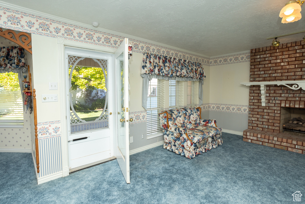 Living area featuring ornamental molding, a textured ceiling, a brick fireplace, and carpet flooring