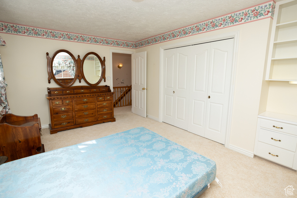 Bedroom featuring a closet, a textured ceiling, and light colored carpet