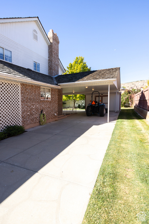 View of parking / parking lot featuring a yard and a carport