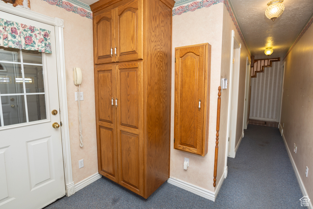 Hall featuring dark carpet and a textured ceiling