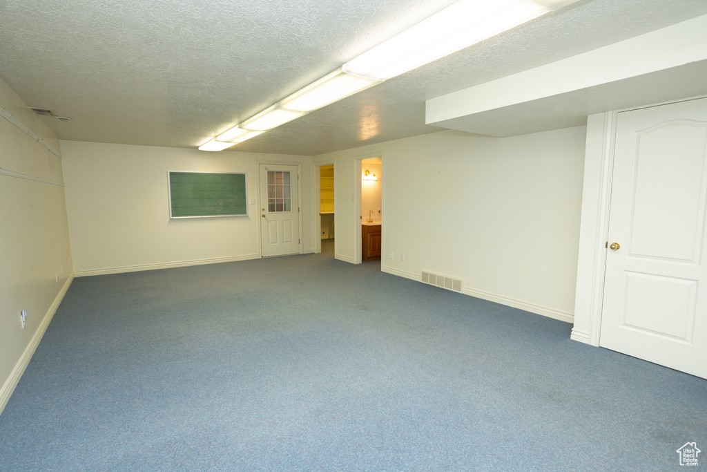 Basement featuring dark carpet and a textured ceiling