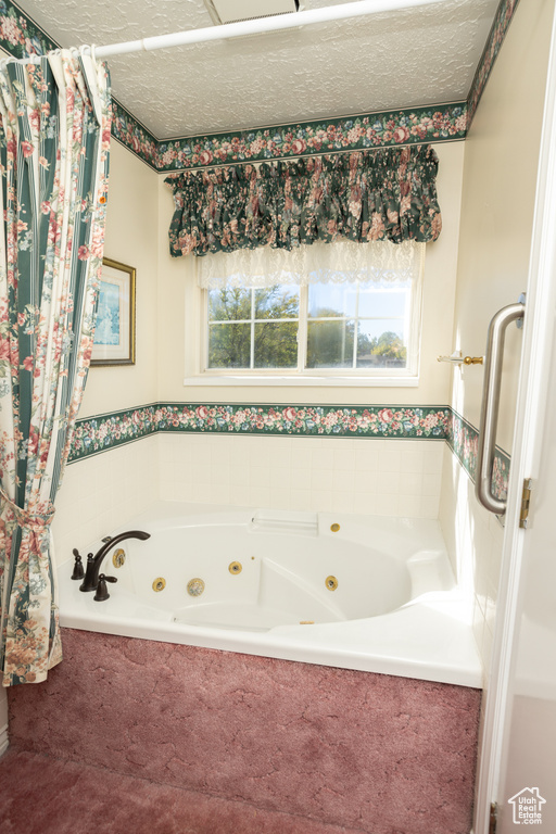 Bathroom with a textured ceiling and tiled tub