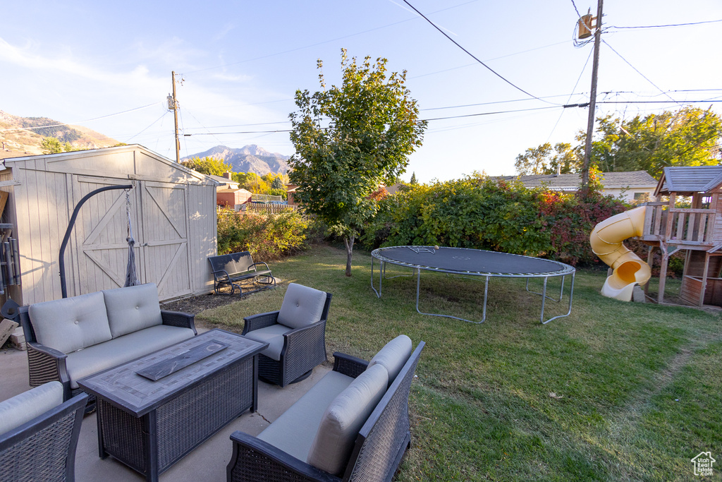 View of yard featuring a mountain view, a shed, a trampoline, and an outdoor hangout area