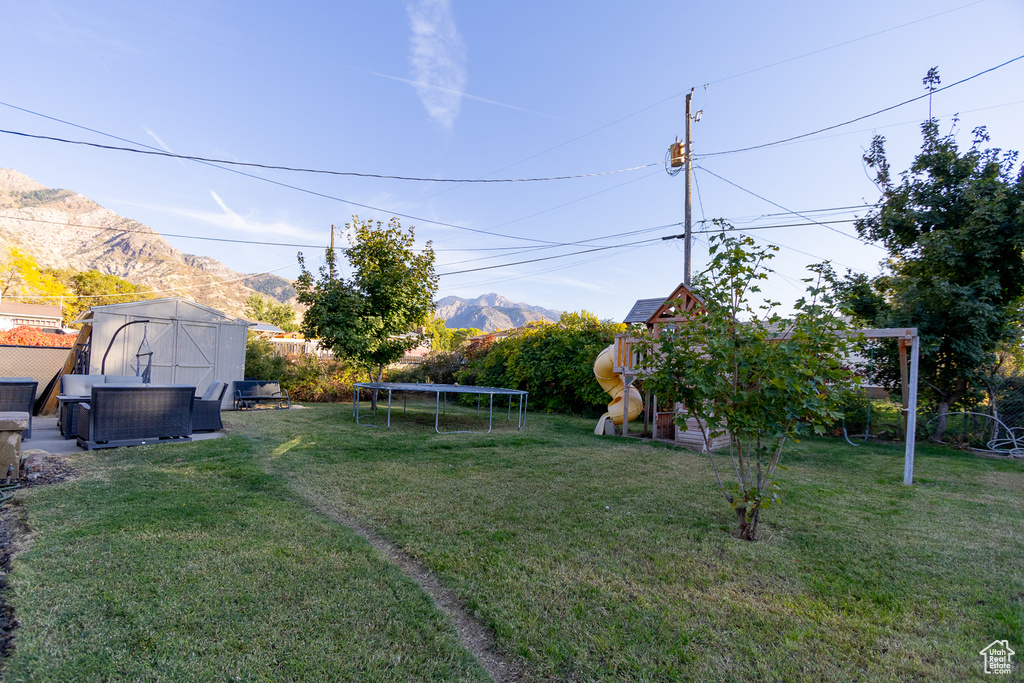 View of yard with a storage shed, a mountain view, and a trampoline