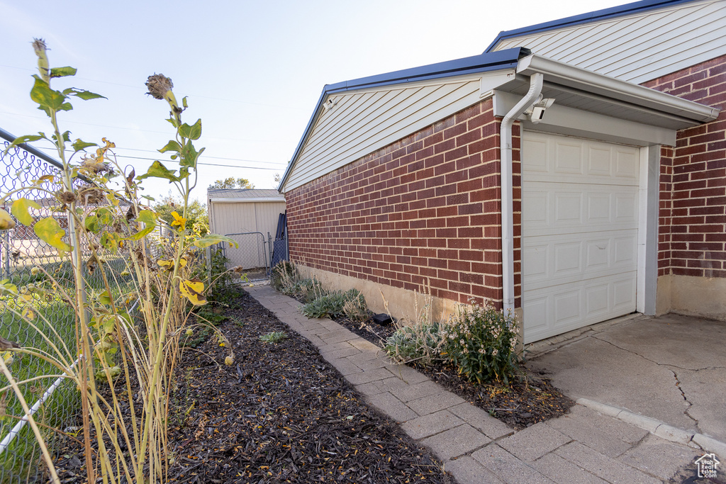 View of side of home with a storage shed and a garage