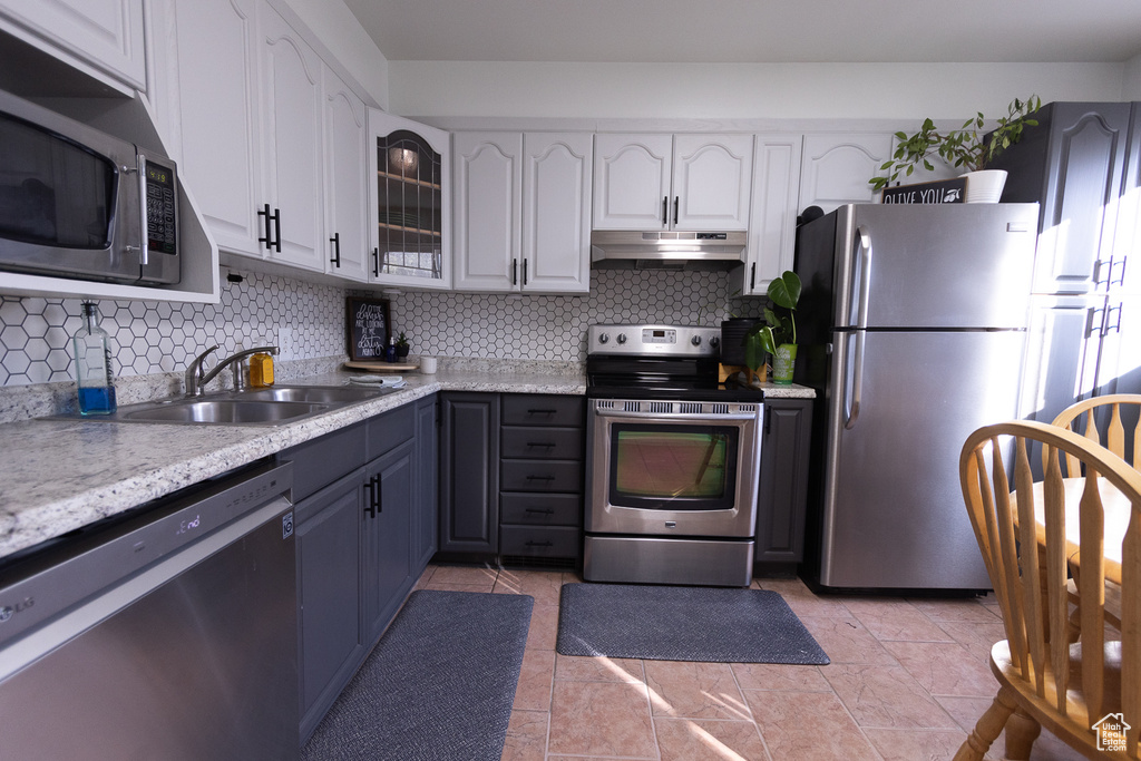 Kitchen with white cabinetry, backsplash, stainless steel appliances, and sink