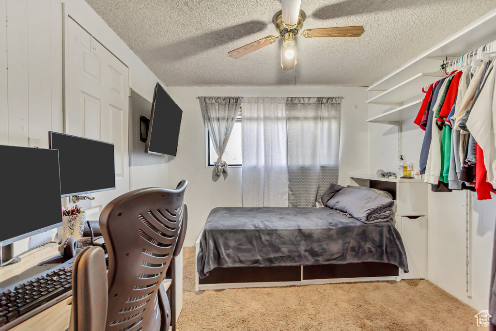 Carpeted bedroom featuring a textured ceiling and ceiling fan