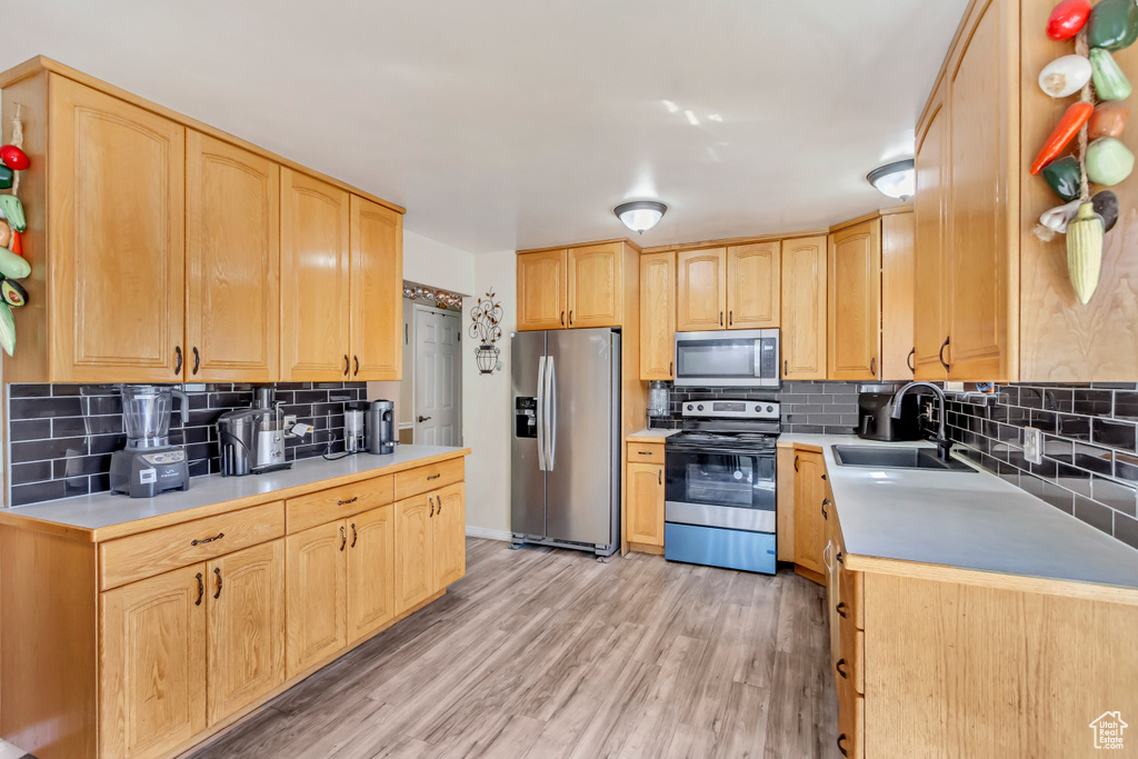 Kitchen featuring decorative backsplash, light hardwood / wood-style flooring, stainless steel appliances, sink, and light brown cabinetry