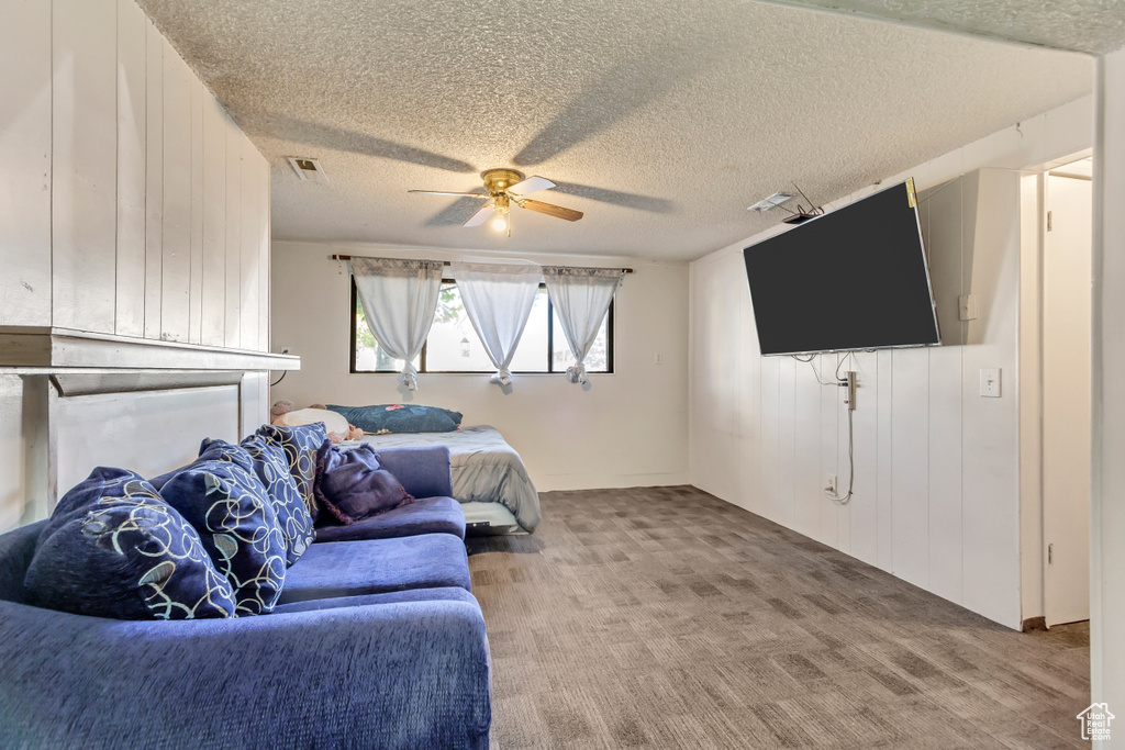 Carpeted living room with a textured ceiling and ceiling fan