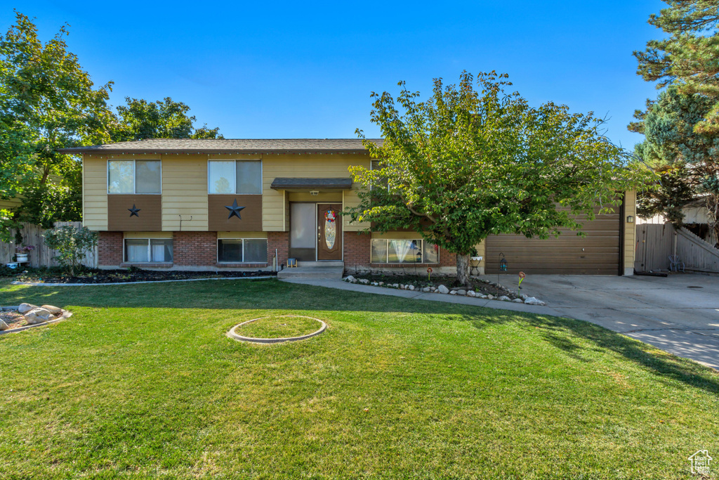 Bi-level home featuring a garage and a front lawn