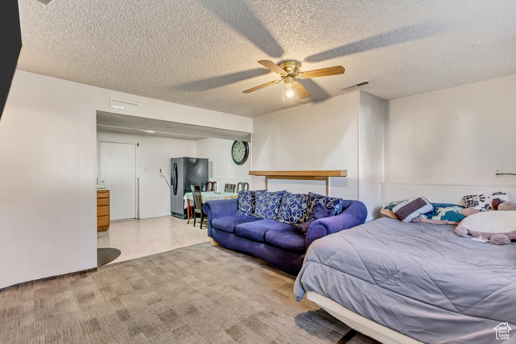 Bedroom with ceiling fan, a textured ceiling, and black fridge