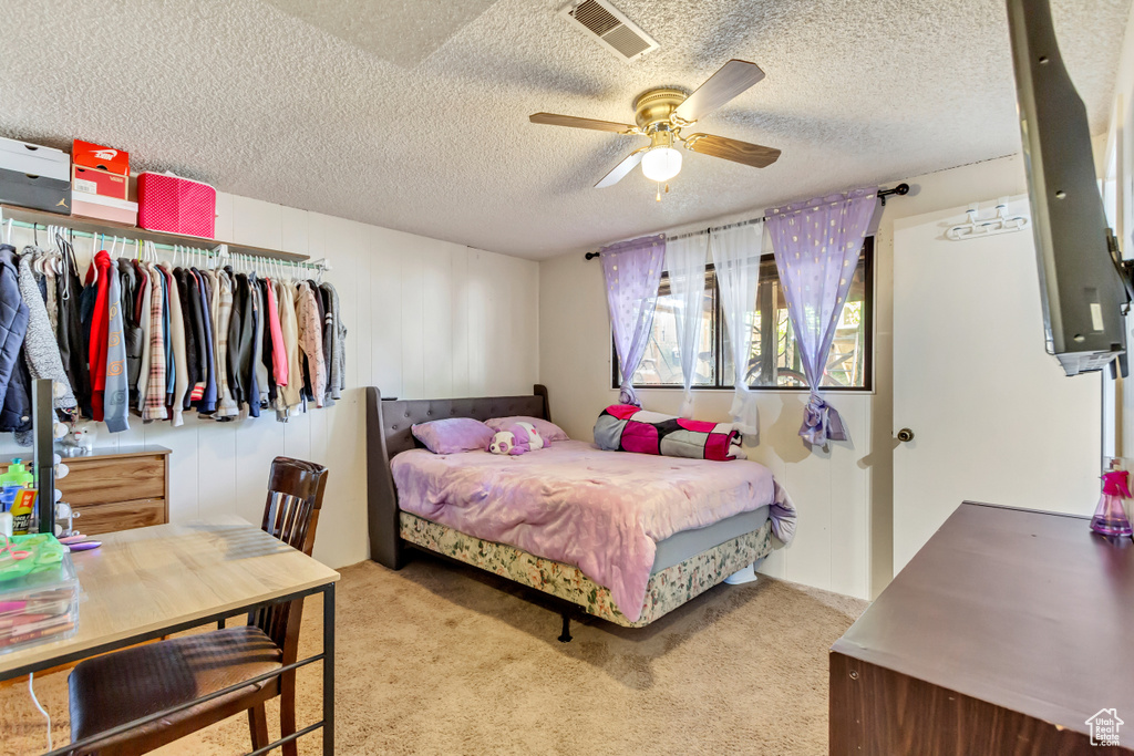 Bedroom featuring a textured ceiling, light colored carpet, and ceiling fan