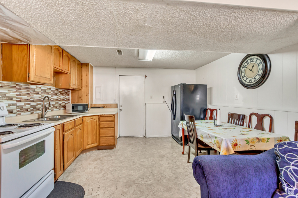 Kitchen featuring white appliances, a textured ceiling, decorative backsplash, and sink