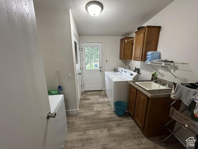 Laundry room with cabinets, sink, dark wood-type flooring, and separate washer and dryer