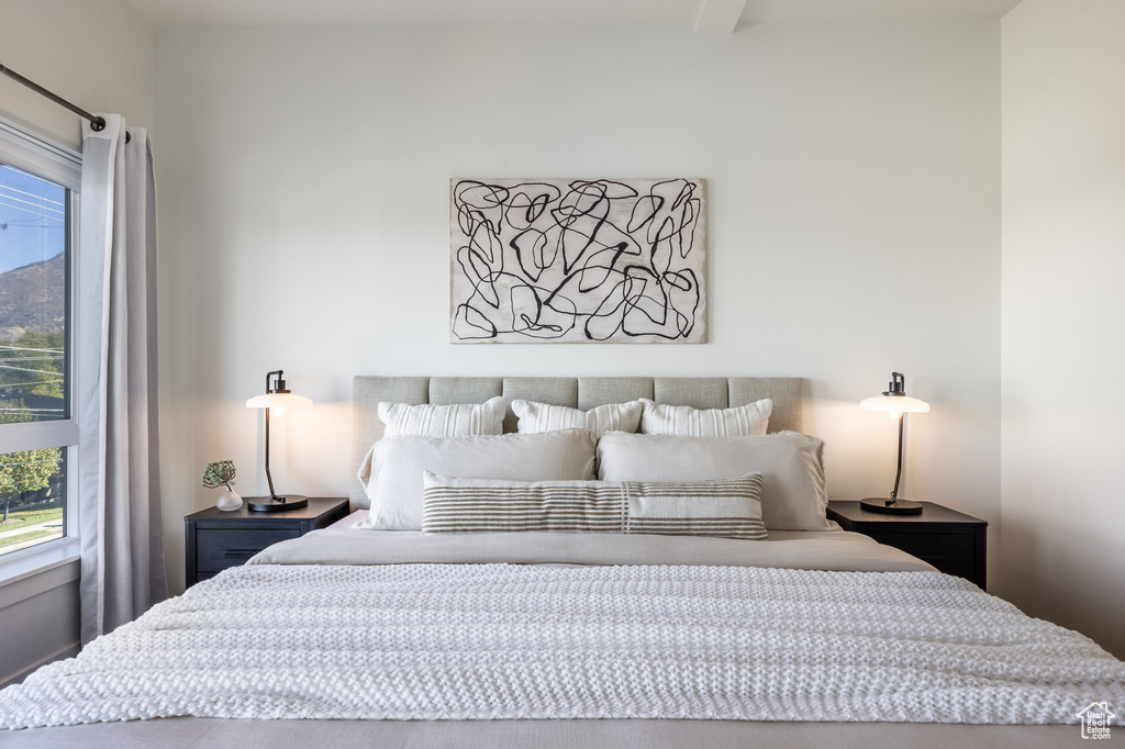 Bedroom with beam ceiling and multiple windows