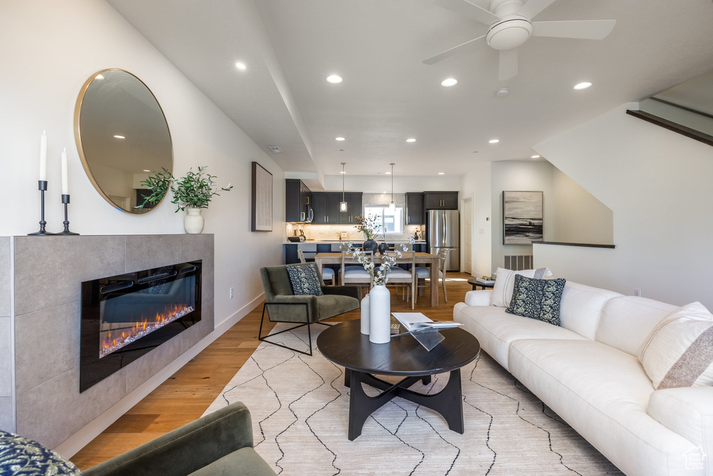 Living room featuring ceiling fan, light hardwood / wood-style flooring, and a tile fireplace