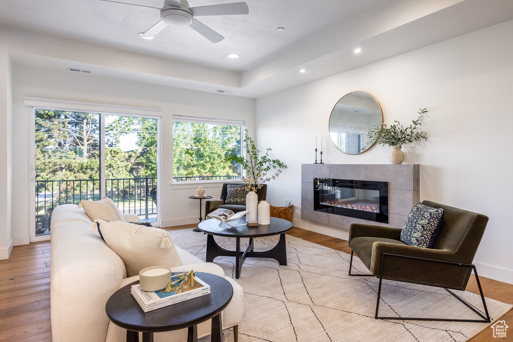 Living room with a tile fireplace, light hardwood / wood-style floors, and ceiling fan