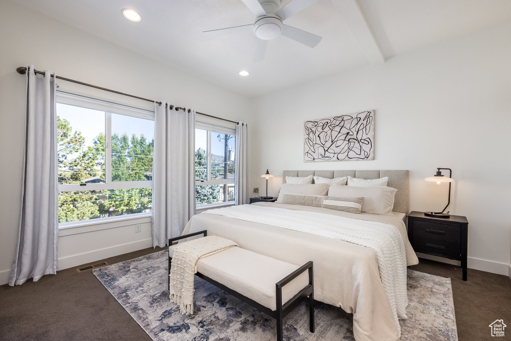 Carpeted bedroom featuring beamed ceiling and ceiling fan