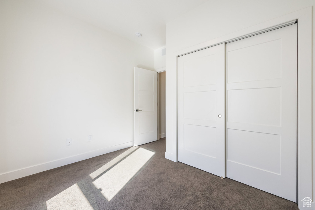 Unfurnished bedroom featuring a closet and dark carpet