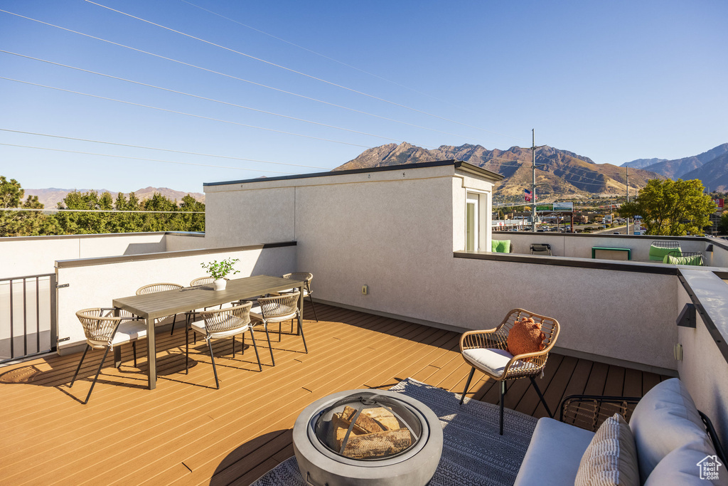 Wooden terrace featuring an outdoor fire pit and a mountain view