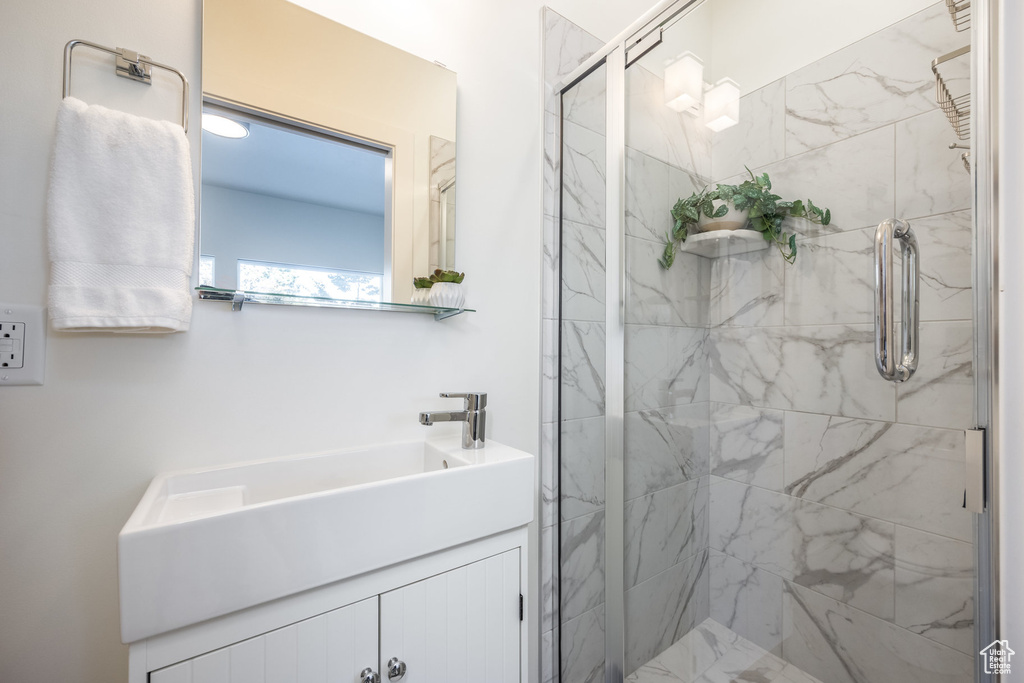 Bathroom featuring a shower with door and vanity