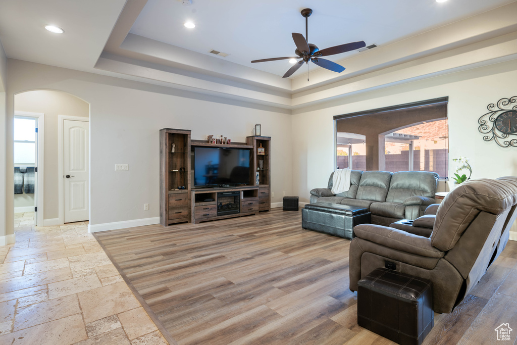 Living room featuring light hardwood / wood-style floors, a tray ceiling, and ceiling fan