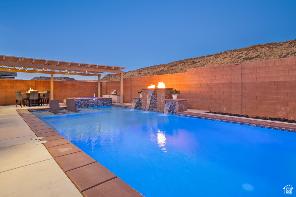 View of pool with an in ground hot tub, a patio, an AC wall unit, a pergola, and pool water feature