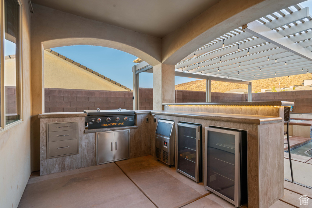 View of patio featuring area for grilling, beverage cooler, an outdoor kitchen, and a pergola