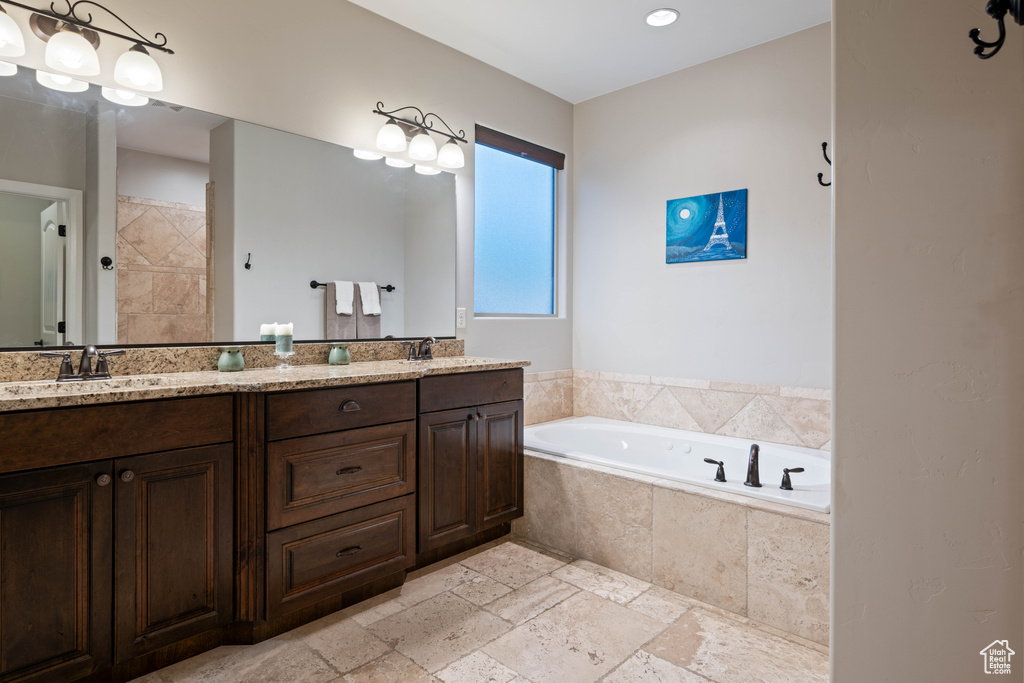 Bathroom featuring vanity and tiled bath