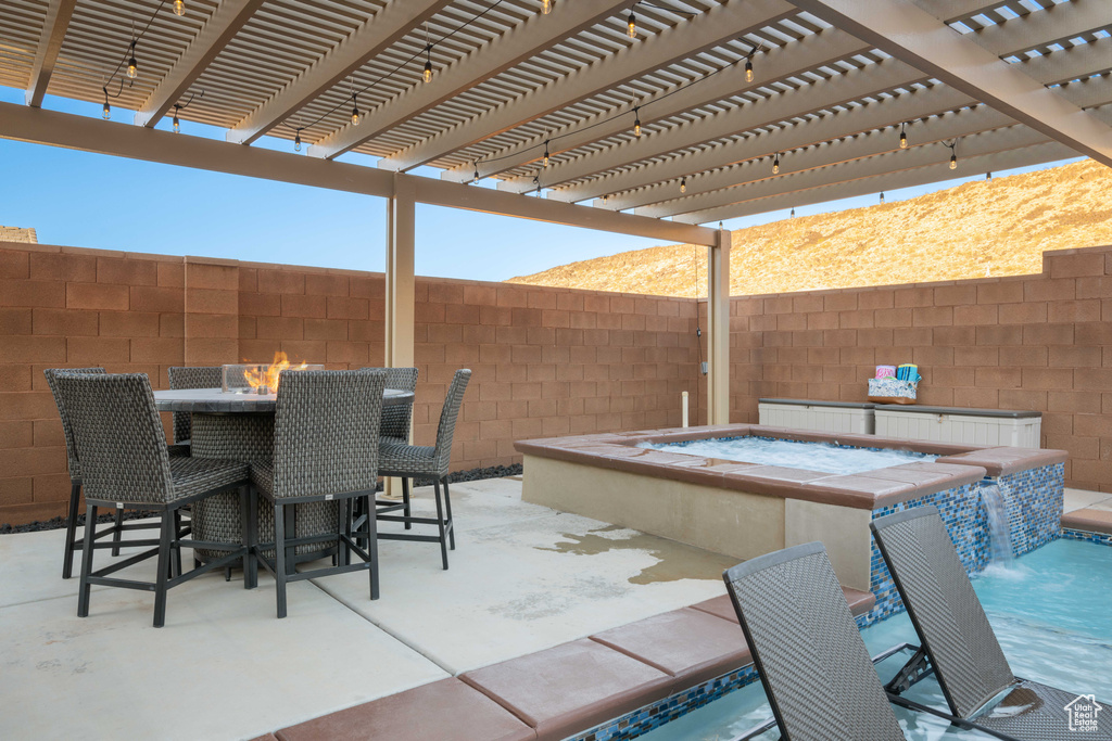 View of patio / terrace with an in ground hot tub, pool water feature, and a pergola