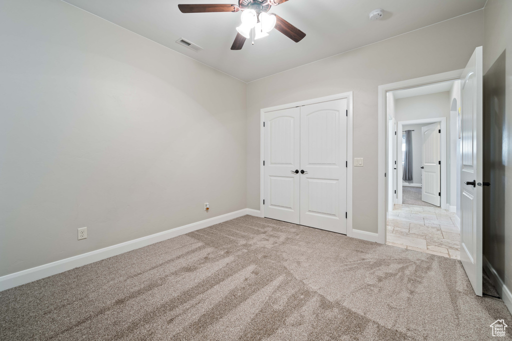 Unfurnished bedroom with light carpet, a closet, and ceiling fan