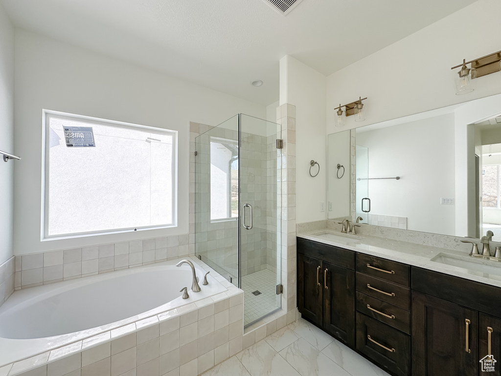 Bathroom featuring double vanity, a garden tub, a sink, and a stall shower