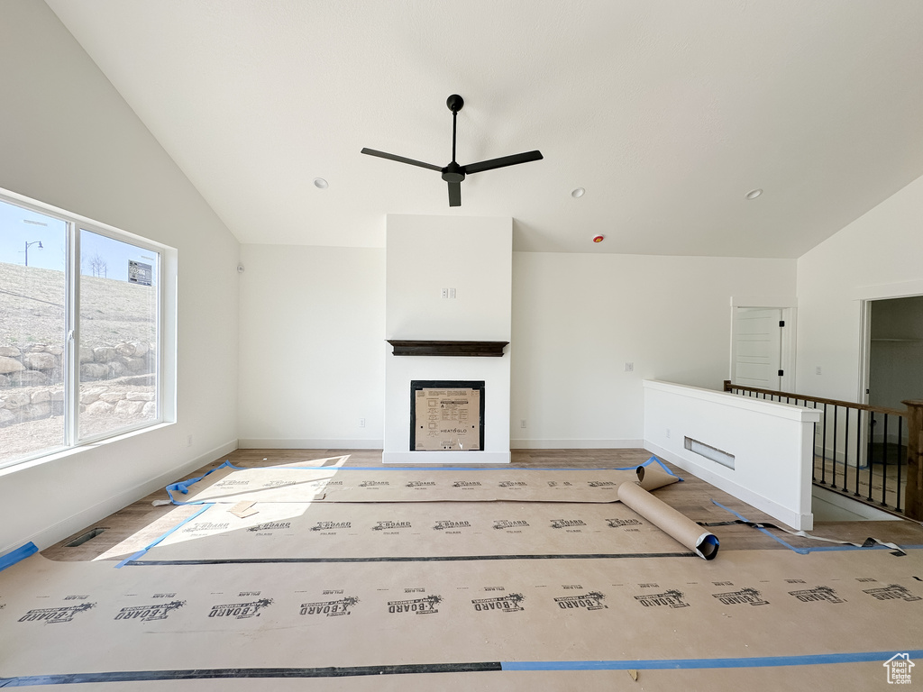 Unfurnished living room featuring a ceiling fan, wood finished floors, vaulted ceiling, and a fireplace