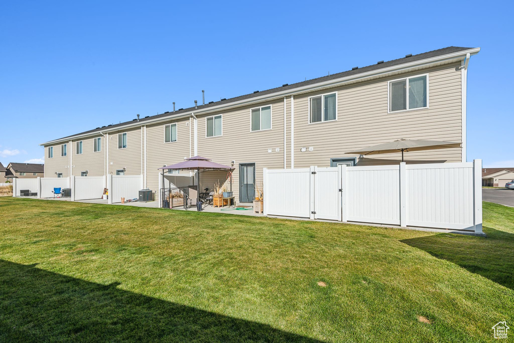 Rear view of property featuring a yard, central air condition unit, and a patio