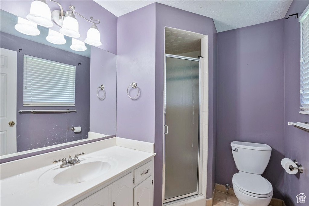Bathroom featuring toilet, walk in shower, vanity, and tile patterned floors