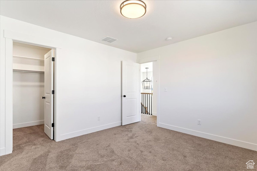 Unfurnished bedroom featuring light carpet, a closet, and a walk in closet