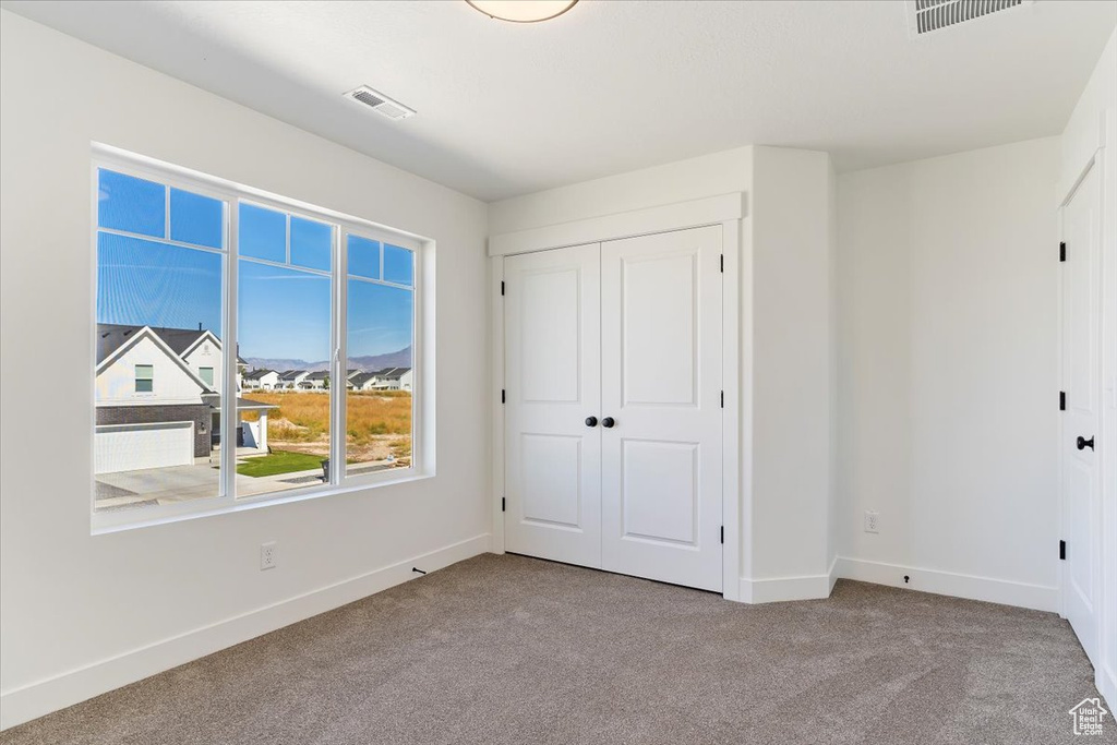 Unfurnished bedroom with light colored carpet and a closet