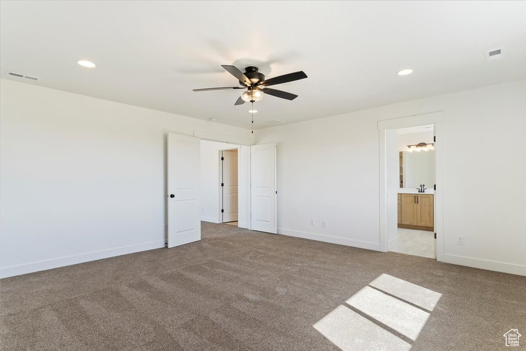 Unfurnished bedroom featuring connected bathroom, ceiling fan, light carpet, and sink