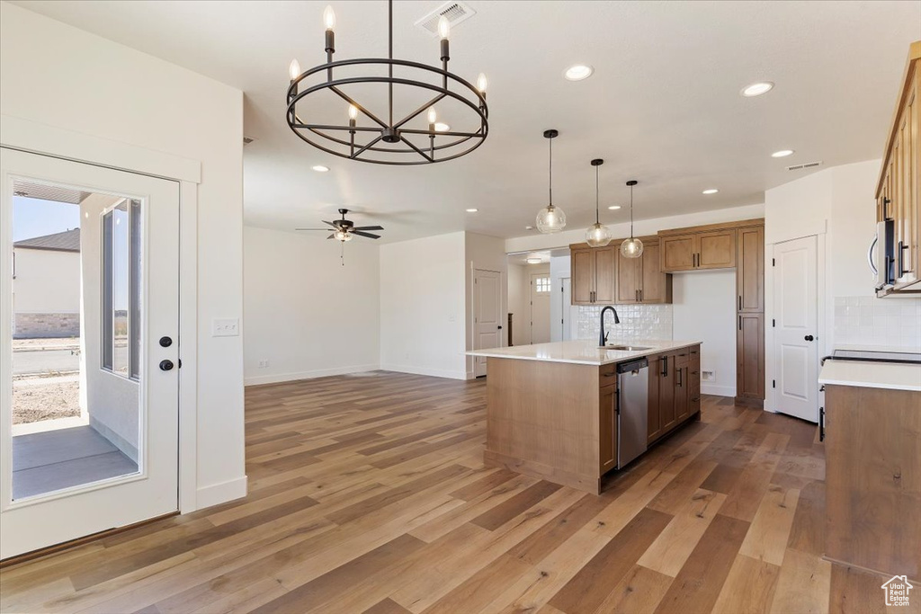 Kitchen featuring sink, an island with sink, stainless steel appliances, and hardwood / wood-style flooring